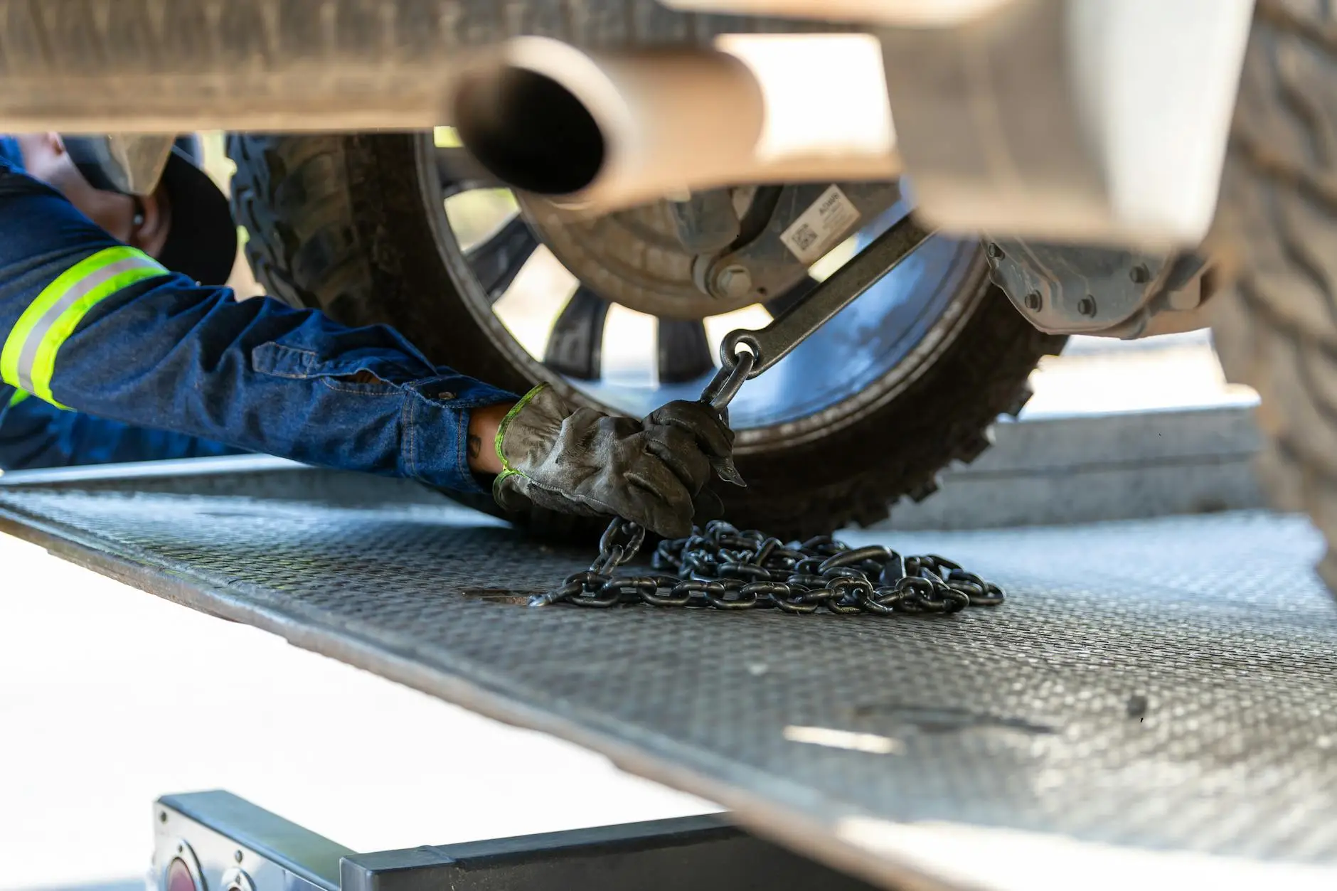 A close-up of a professional tow truck operator securing a vehicle with high-quality straps to ensure damage-free transport.
