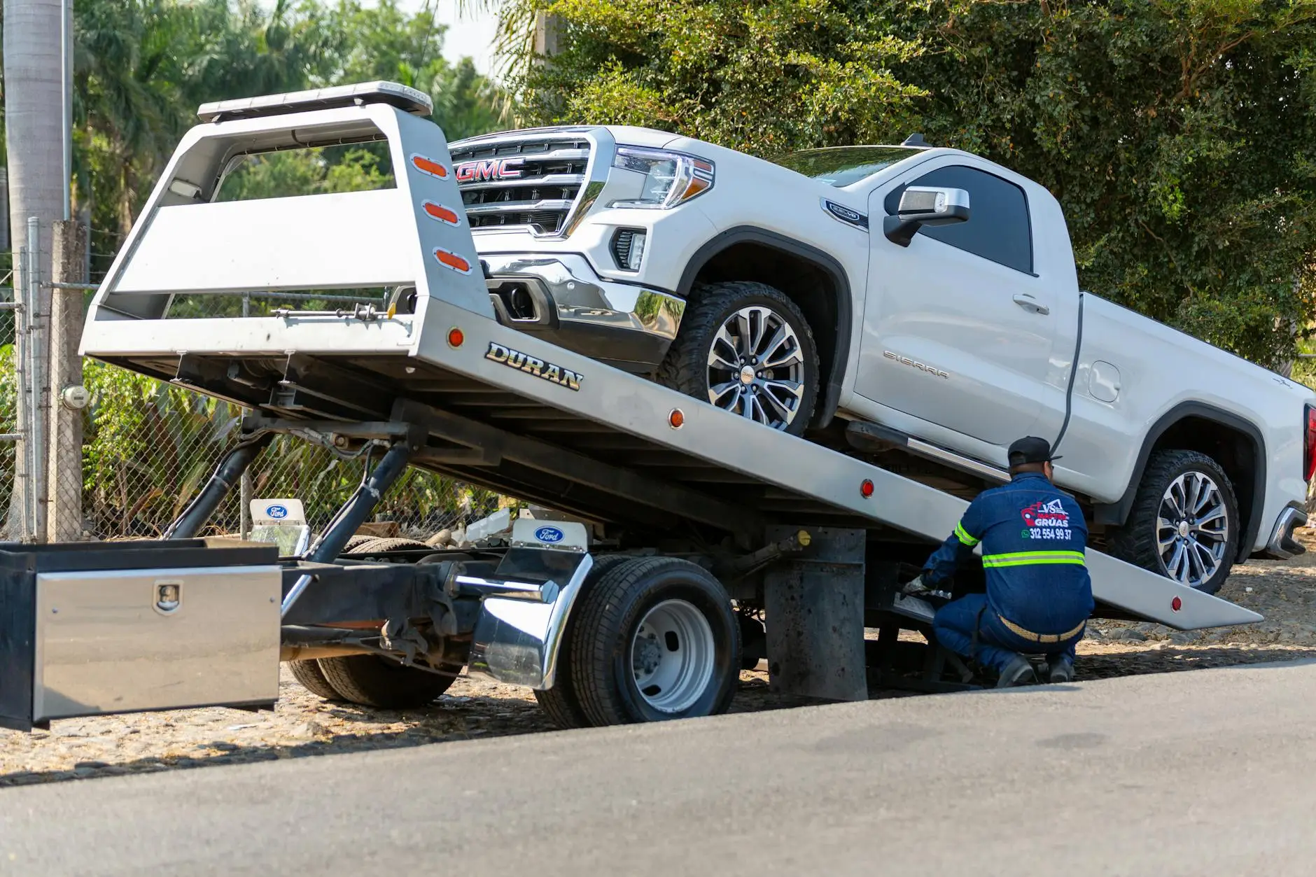 A close-up of a tow truck's hydraulic controls being operated by a professional in safety gear during a night recovery in Warren.